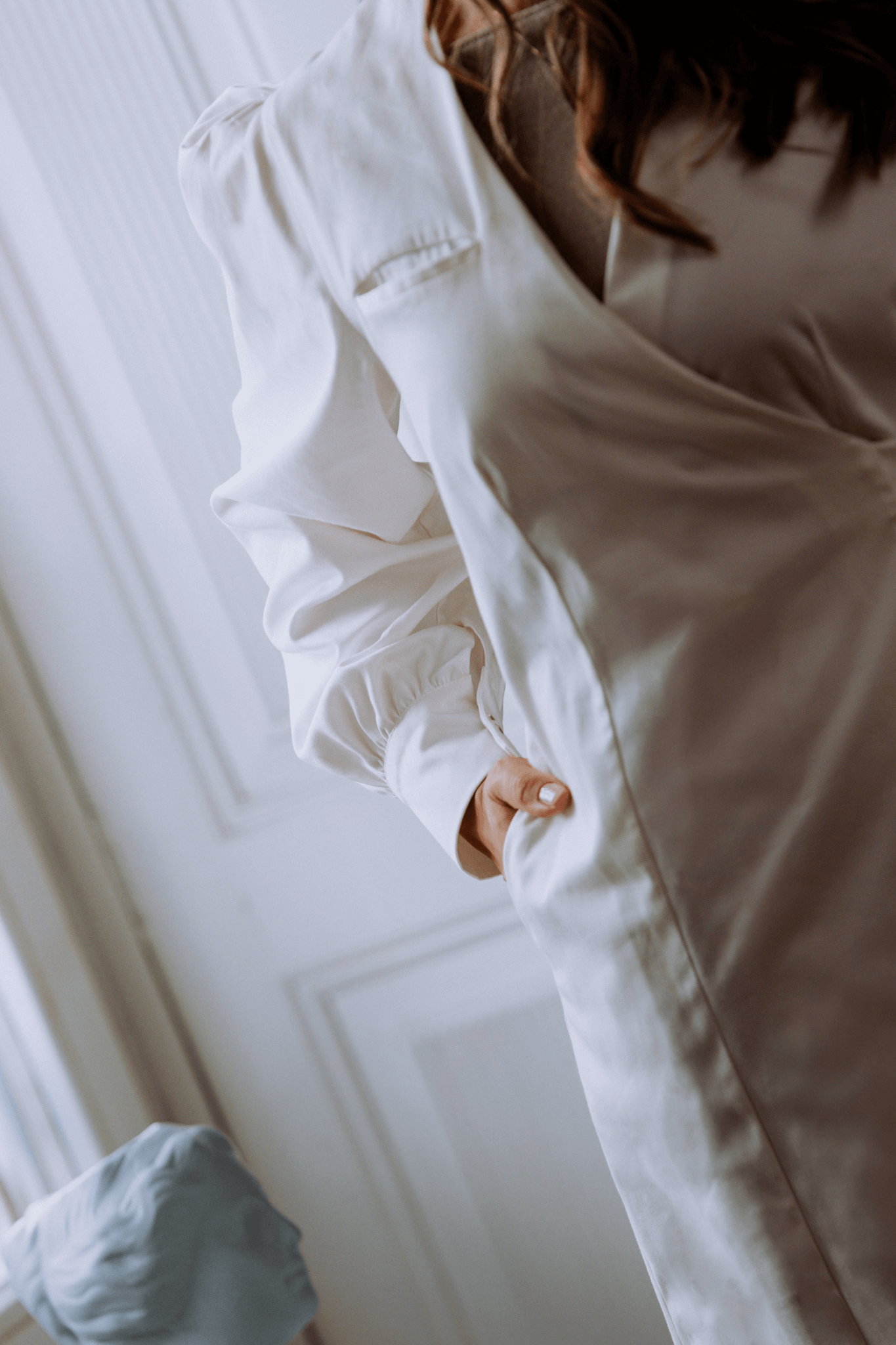 Close-up of a model wearing a white bata Agnodice with voluminous sleeves and a stylish pocket detail.